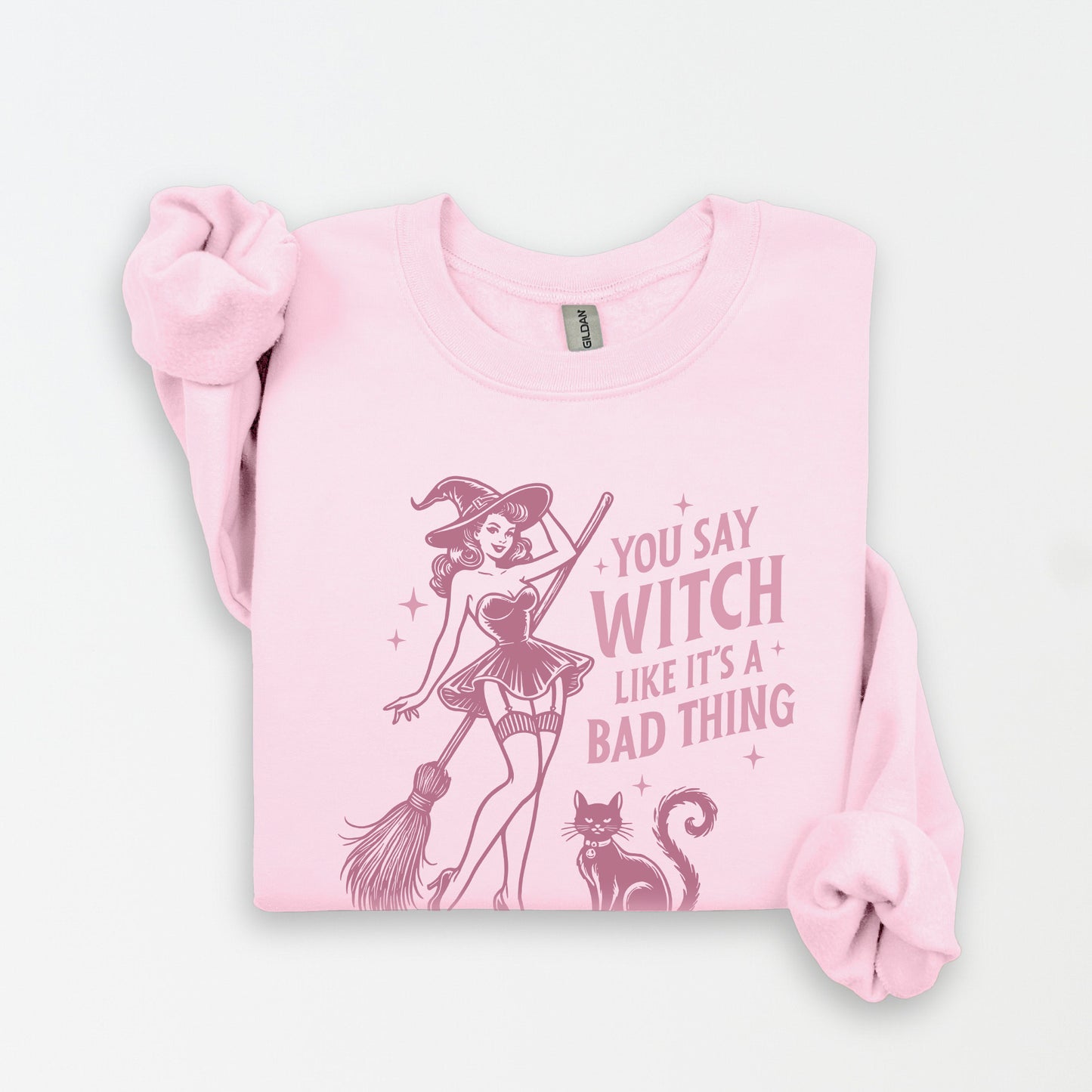 Pink sweatshirt with a graphic of a witch and text on a white background