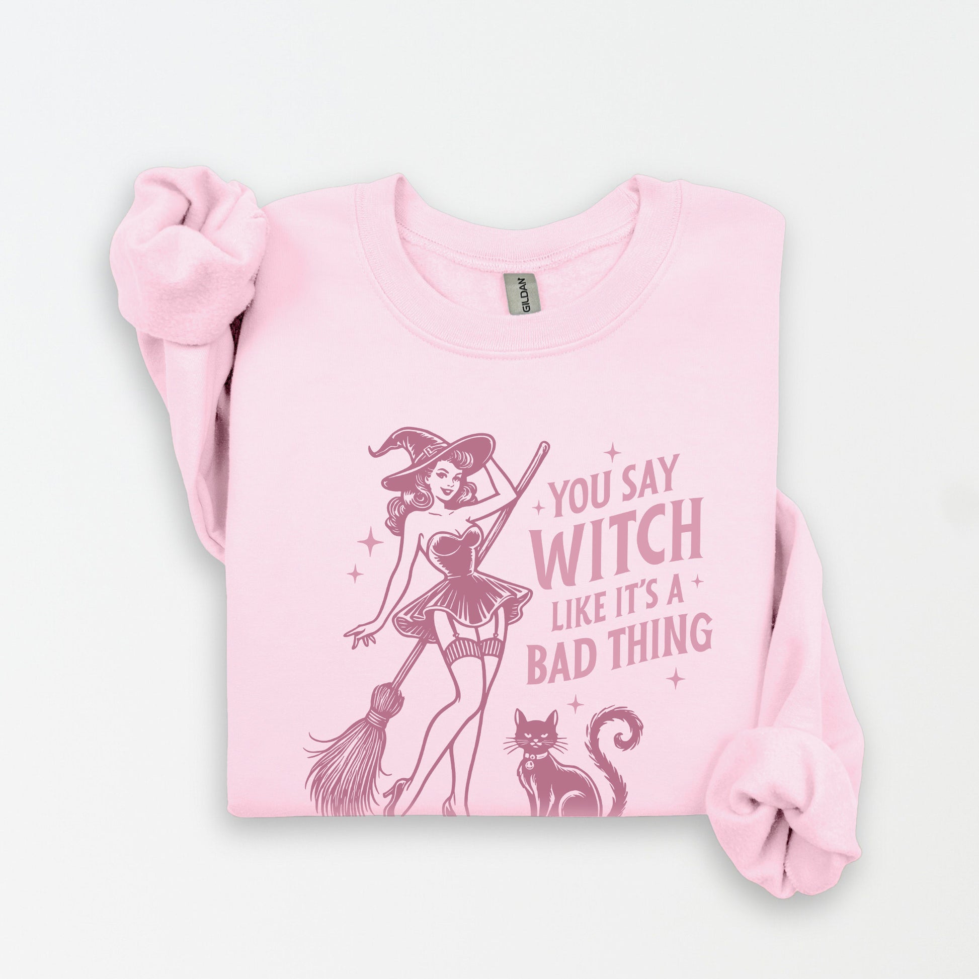 Pink sweatshirt with a graphic of a witch and text on a white background